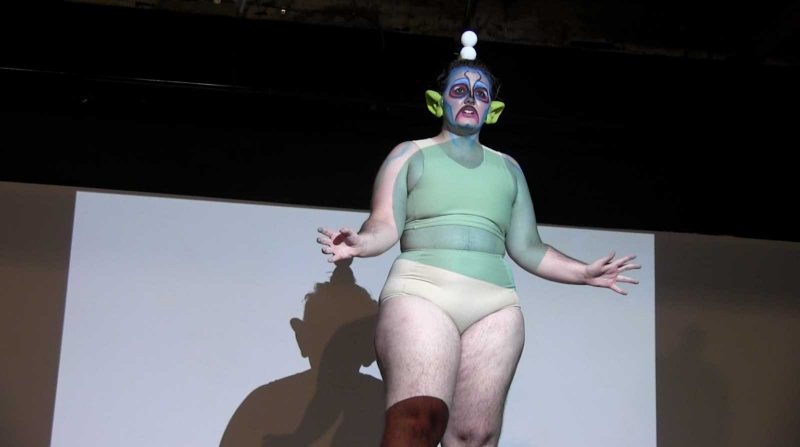 Lee performing in drag with costume ears, face makeup, and nude underwear on.