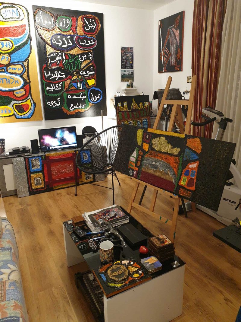 Studio space with easel and paintings on the wall.