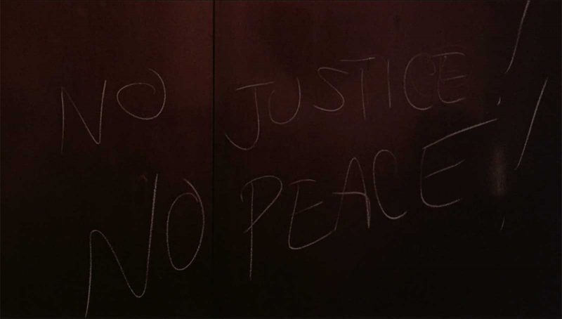"NO JUSTICE NO PEACE" scratched onto a wall