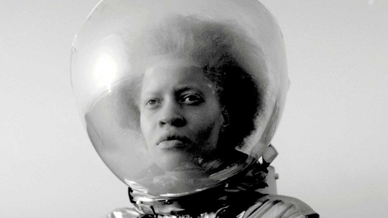 Close-up black and white shot of a black woman in a space suit.