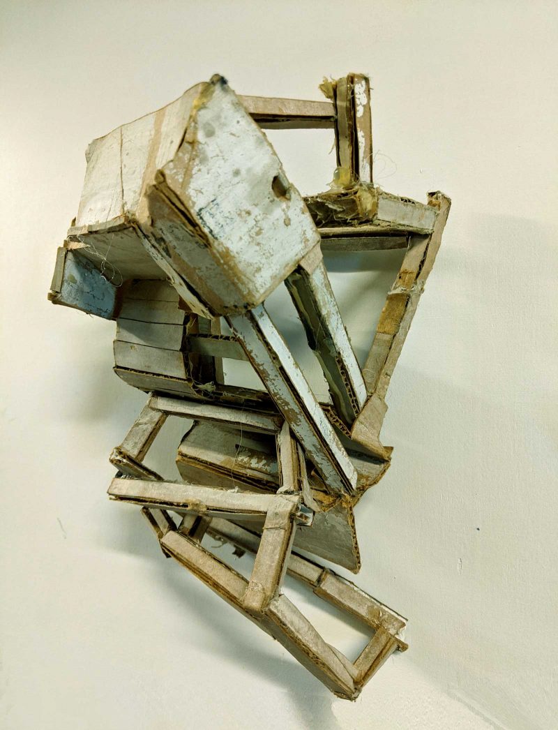 Cardboard sculpture of geometric shapes connecting in a disheveled architectural mass