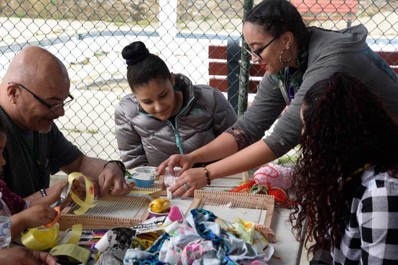 Salina helping others with their art at a picnic table outdoors.