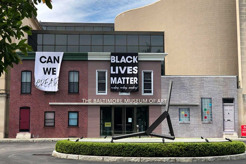 Exterior of the Baltimore art museum with "Can we breathe" and "Black lives matter" printed on fabric that hangs from the museum.