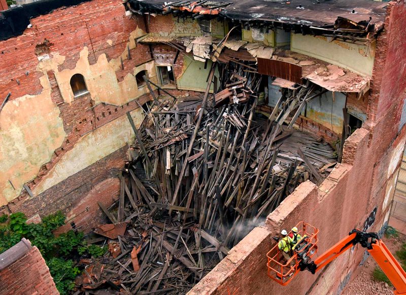 Aerial view of the partially demolished Mayfair Theatre in Baltimore, with two workers on the side breaking it down. 