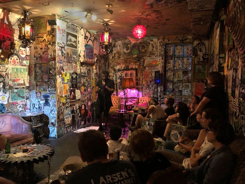 Alex Smith reading from a book in front of a crowd at Tattooed Mom.