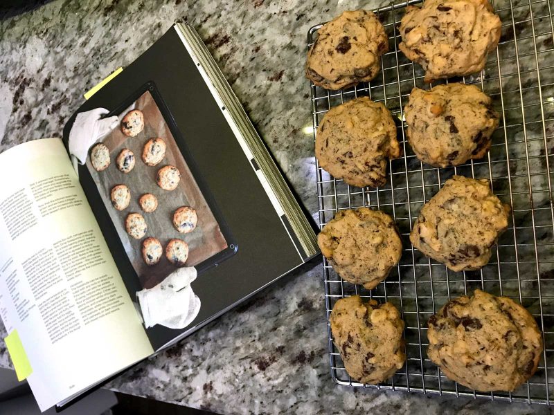 Olafur Eliasson's cookbook, open to a page that shows chocolate cookies, sitting open on a kitchen counter next to a tray of freshly baked cookies.