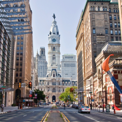 Philadelphia city hall captured from north broad street, with PAFA's paintbrush sculpture visible on the right amongst the tall city buildings.