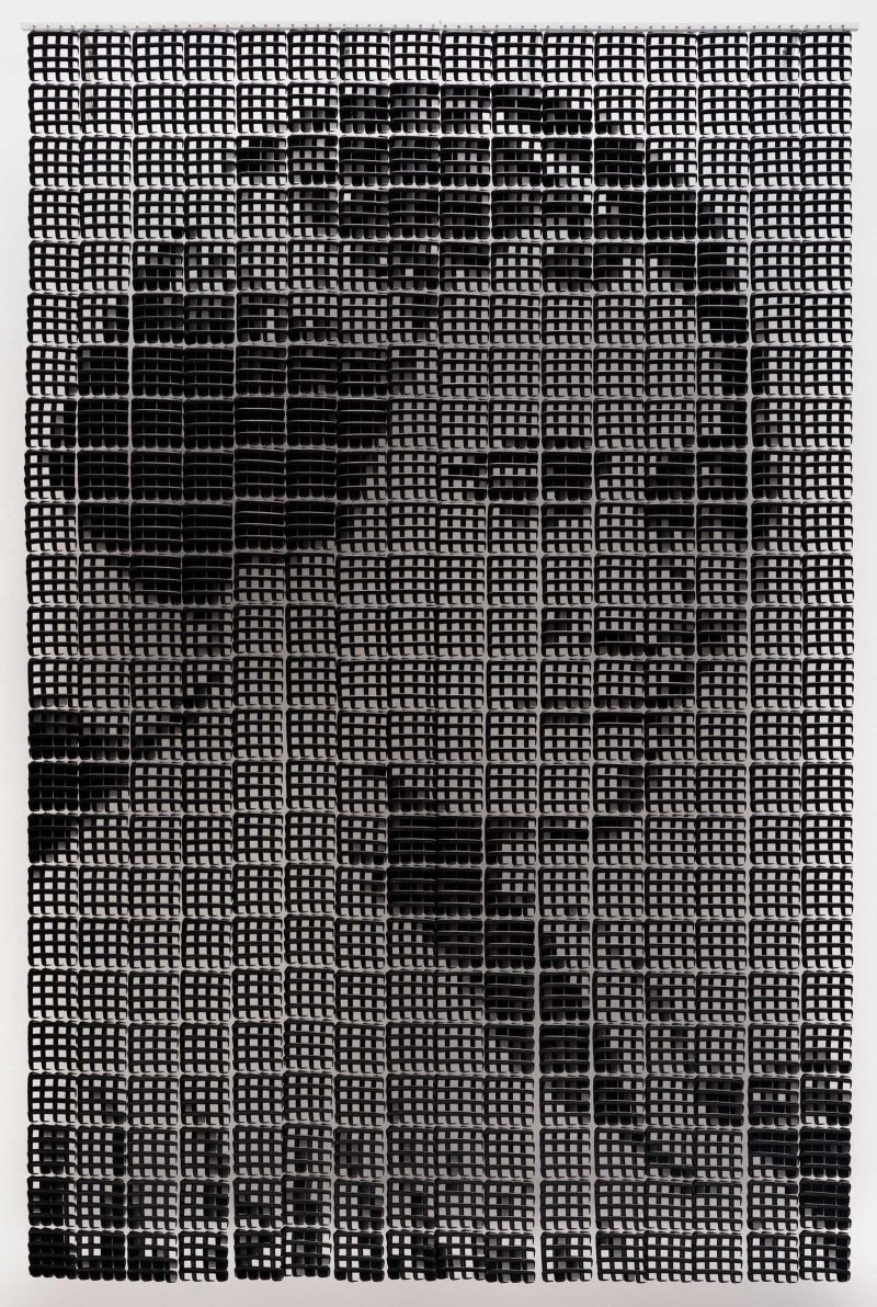 Large portrait of a black woman constructed out of black hair combs, overlapping in shaded areas. 