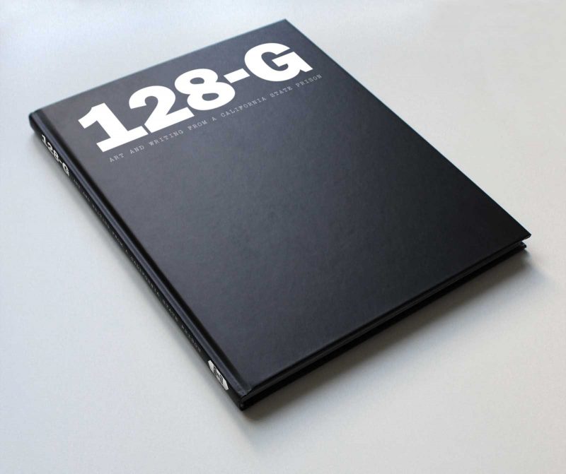 Black hardcover book "128-G" on a gray table.
