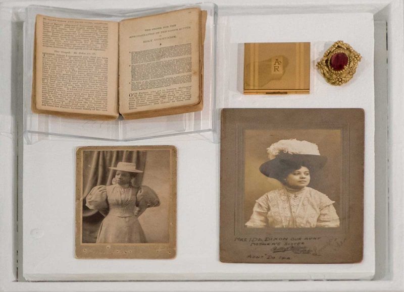Personal belongings of Anna Russell Jones, including a book, jewelry, a monogrammed case, and photo portraits, in a glass display case.