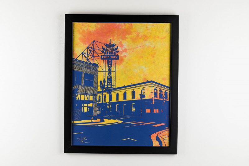 Blue paper cut artwork of a city corner, featuring a large restaurant sign that says "chop suey hung farlow," on an orange and yellow watercolor background.