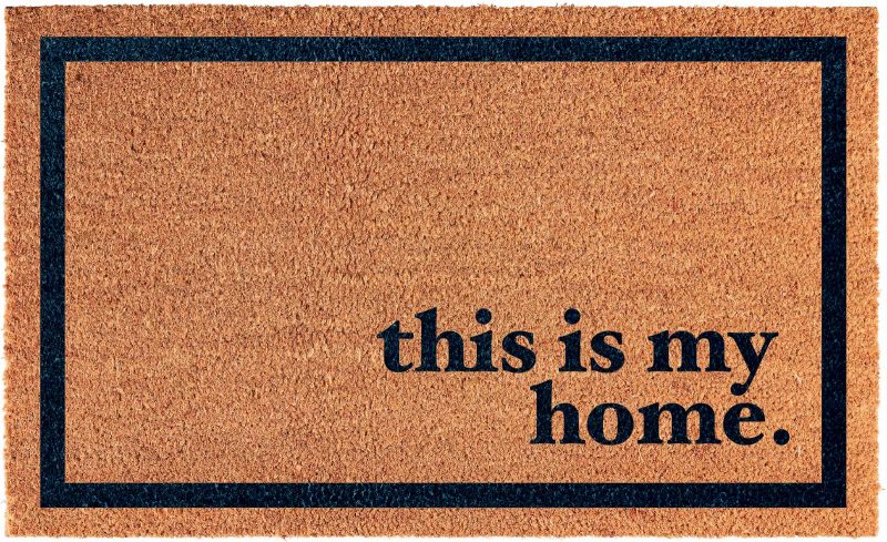 Digital rendering of a brown doormat with a black border and the words "this is my home." in black near the bottom right corner.