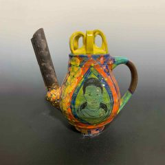 Colorful ceramic teapot with exaggerated spout and handle, with a portrait of Mae Jemison drawn in the center of the body of the pot.