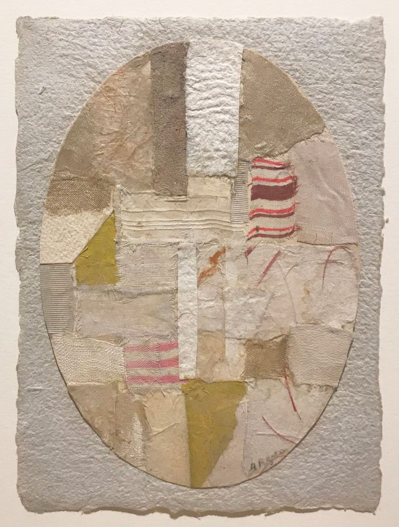 Collage with an oval in the center, on top of a silvery gray background, inside of white are patches of muted olive, tan, beige, and light red textures and patches.