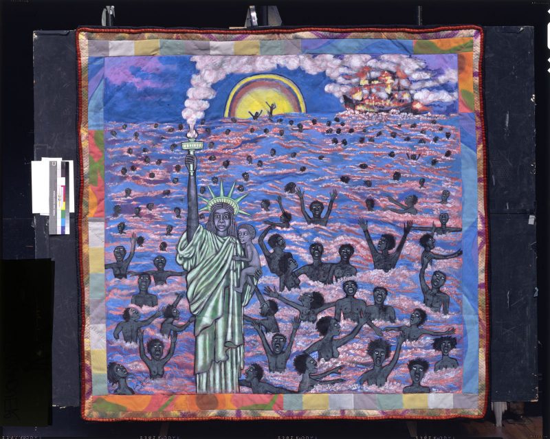 Illustration on a quilt of the Statue of Liberty as a black woman holding a child in one arm and the torch in the other, in front of a sea filled with black people fleeing a burning ship behind them, visible near the horizon.