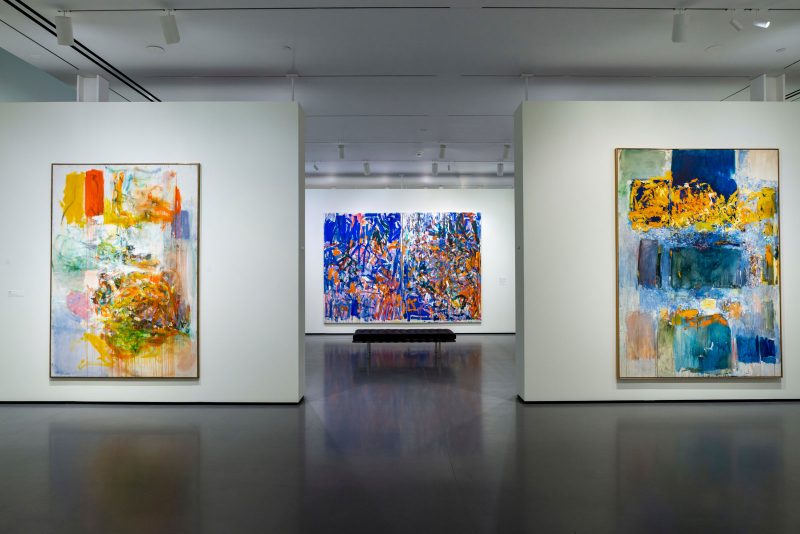 Installation view of three large abstract paintings of brush strokes of various sizes on white backgrounds, hung on white gallery walls in the Baltimore Museum of Art.