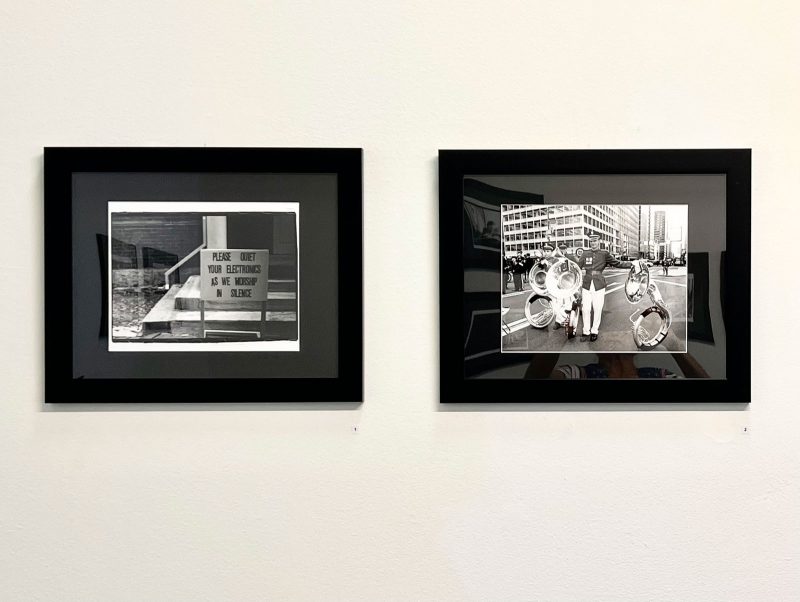 Two black and white photos hang in black frames with black matte side by side on a white wall; left: a church sign says "please quiet your electronics as we worship in silence; right: a man in a marching band uniform stands in the middle of the street with two tubas resting on the street next to him, he props the horn of each up to display them.