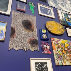 A photo of a blue gallery wall, covered with art and textiles.