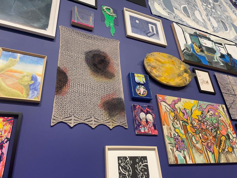 A photo of a blue gallery wall, covered with art and textiles.