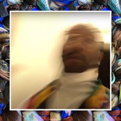 A blurry selfie of rod jones ii-- a Black person with short hair and facial hair, wearing gold glasses, a white turtleneck shirt, and a cardigan-- collaged on top of a detail image of rod's work, featuring many multi-color wigs and braided strands of hair that are woven into one larger braided pattern.