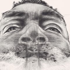 Black and white drawn self portrait of the artist, a bearded black man in extreme close up looking down at the camera. Threads cross his nose.
