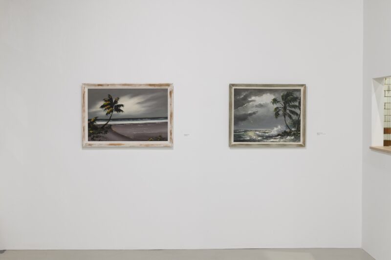 In a corner of an art gallery are two framed paintings by Harold Newton, member of The Highwayman Collective, on a wall, both showing moody, moonlit landscapes that suggest calmness and solitude in beauty.