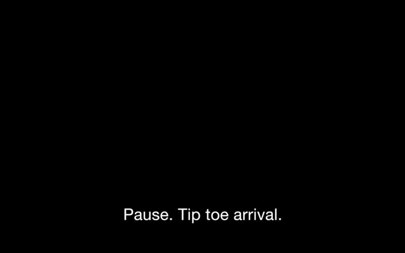 A pitch black rectangle, which is taken from a video by Carolyn Lazard, holds white text on the bottom that says, “Pause. Tip toe arrival.”