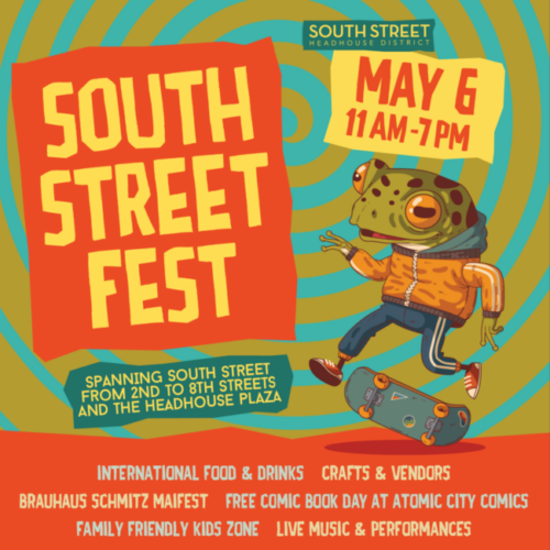 A frog in an orange bomber jacket some blue track pants and red converse kickflips a skateboard. In orange and yellow are banners announcing South Street Art Fest happening May 6 11Am-7PM.