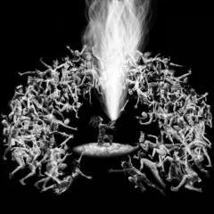 A square black and white image. At the center is an almond shaped elliptical with a person in feathered dress shoots fire like spark trails from an object in their hands. Around the fire the formation of a house shoe of people in variety of poses and costume surround.