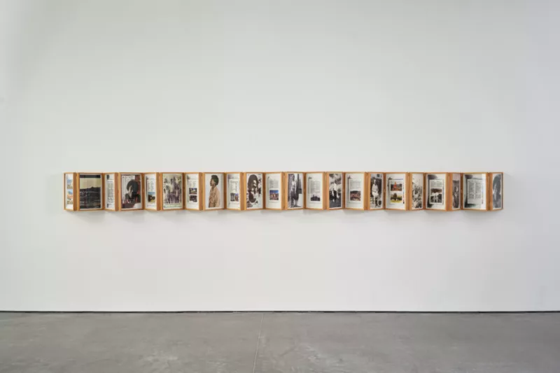 A long horizontal stretch of images and letters collaged in frames forming an accordion across the wall. The images show people, landscapes, buildings. Each intermingled with texts.