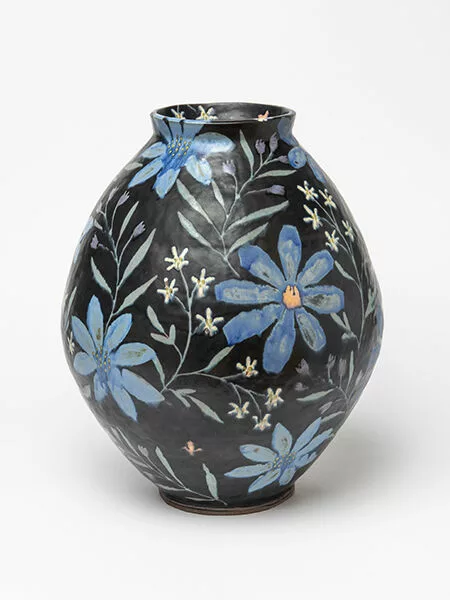 A ceramic jar mostly black with blue and white flowers.