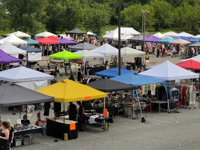 A parking lot full of vendors under pop up tents.