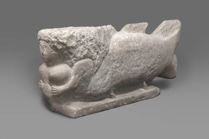 A limestone sculpture by William Edmondson titled Mermaid shows a woman in a position similar to the masthead of a ship with a fish body appearing from her torso.