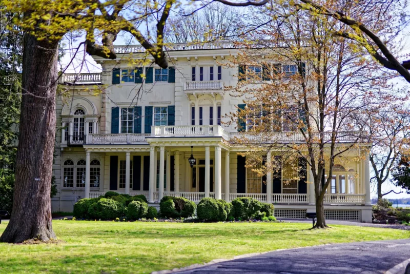 Glen Foerd historic house, a white three story house with a Grande colonnade and balcony sitting in a wooded area on the river.