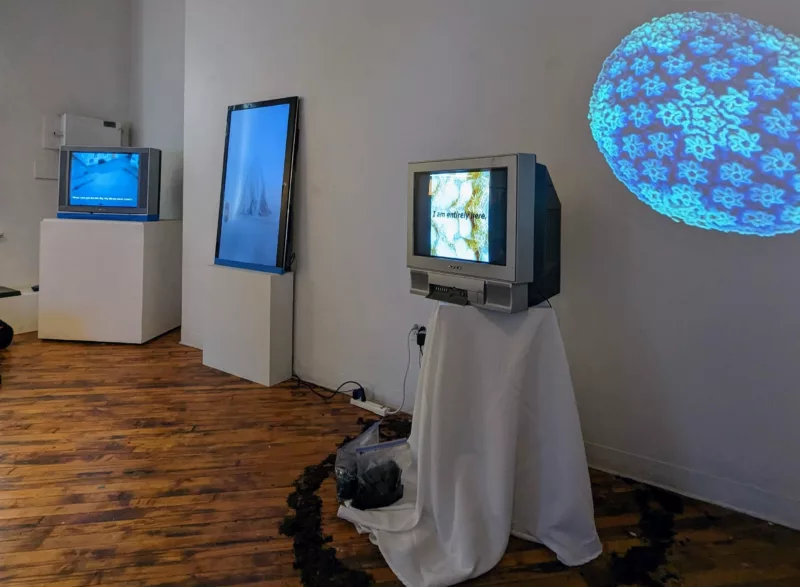 A gallery wall is installed with four different era video screens, from a cathode ray tube to a flat panel screen to a projection on a wall. The different technologies through the ages remind you of how technology has been with us for a long time but is ever changing, requiring devices to change and people’s use patterns to change as well.