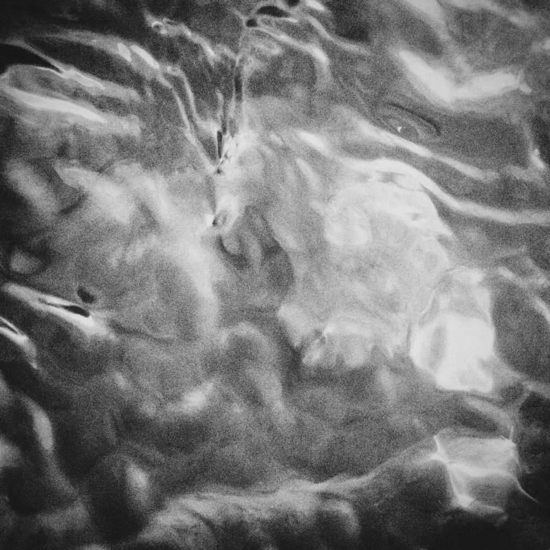 A black-and-white image of swirling water with many frothing white areas surrounded at the border with deep dark grey and black.