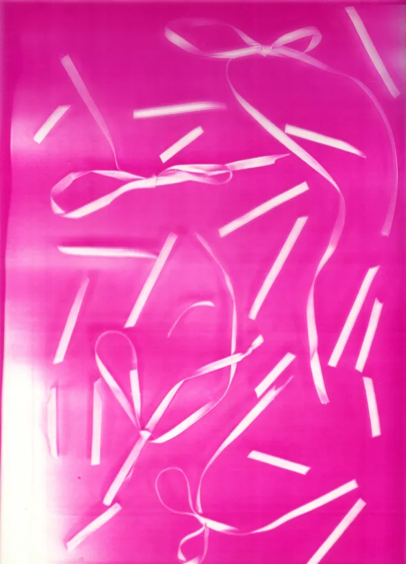 A bright pink images shows white ribbons cut into small segments floating as if in a pink cocktail of ether.