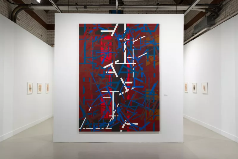 A large red, white and blue painting sits on a partial wall in a gallery, its highly abstract pattern evocative of many layers of screens in front of a red background that suggests architecture.