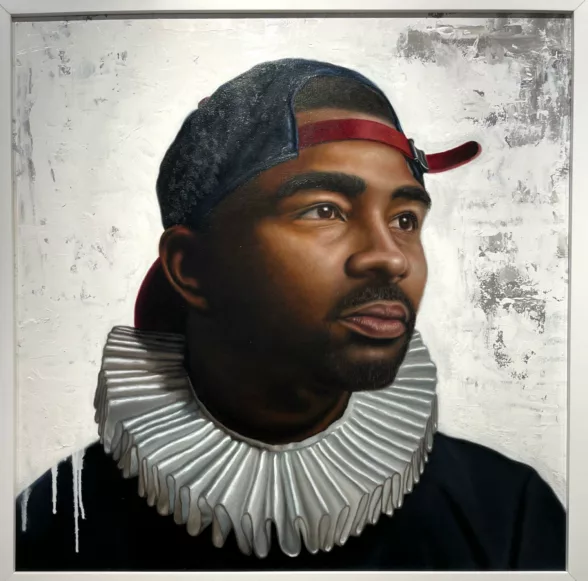 A painted portrait of a young Black man shows him staring off into the far right distance as if looking into the future, his baseball hat on backwards like a contemporary youth and around his neck is a white accordion-pleat “ruff” worn by men and women pictured in Old Master paintings.
