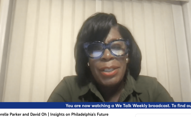 A black woman wearing glasses sits in front of vertical blinds that are closed, and speaks into a camera. She is answering questions posed to her from a grassroots journalism platform, We Talk Weekly. The woman, wearing a dark green shirt and sporting gold earrings and a smart haircut, might be the next mayor of Philadelphia.