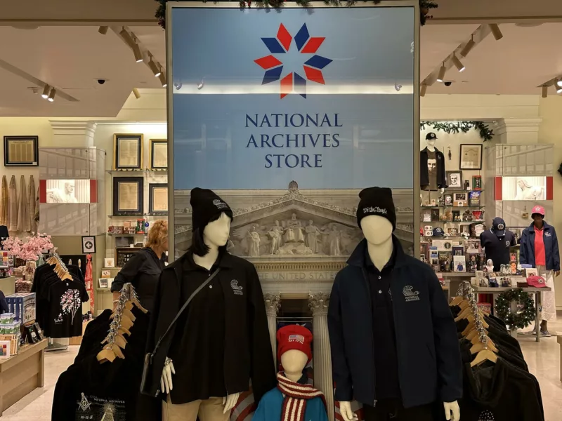 A gift shop entrance is labeled National Archives Store and in front of it are three manikins of a couple and a chile, all wearing merchandise from the store.