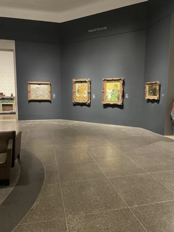 A round museum room called Resnick Rotunda shows four old master paintings by Vincent Van Gogh on a dark grey wall. There is nobody in front of the popular Van Gogh paintings.
