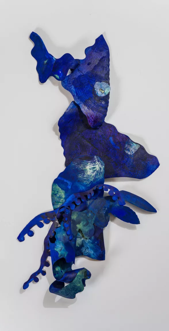 A dazzling blue cut paper piece is on a wall, its assemblage of pieces adding up to a riverine meander, with undulating edges, jarring rabbit ears and curled paper at the bottom.