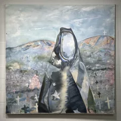 In a painting, a faceless figure wrapped in what looks like a tattered Stars and Stripes flag stands, icon-like in front of two mountains and a plain dotted with crosses signifying graves.