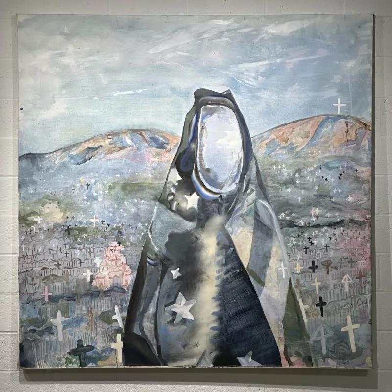 In a painting, a faceless figure wrapped in what looks like a tattered Stars and Stripes flag stands, icon-like in front of two mountains and a plain dotted with crosses signifying graves.