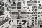 A detail of a larger installation shows a grid of drawings in black and white that sums up a message that is not clear but seems urgent,