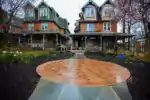 A Victorian-era twin house has an elegant and artistic treatment in front which is a wide orange circle which seems made out of tile.