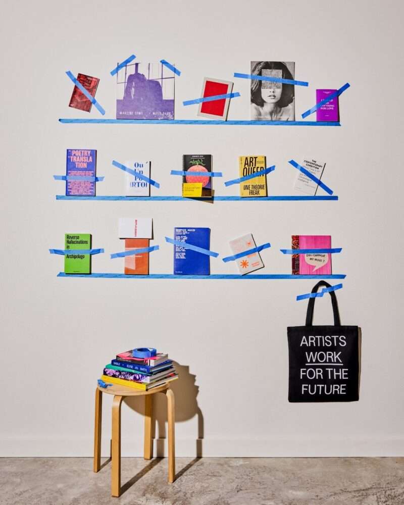 A poster image shows shelves with books taped to them with blue painter's tape and a stool at the bottom with books stacked and a black tote bag with the message, in white: Artists Work For The Future
