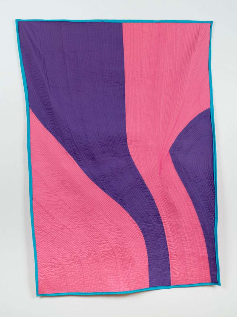 A large quilted cotton cloth wall hanging shows four areas of alternating pink and purple color. The stitching is extreme and the momentum of the works suggest the downward cascade of a river. 