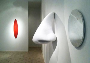 Justen Ladda, "Seven Mirrors and a Nose" installation featuring "white nose", polyester batting and fabric over stainless steel wire frame, "silver round mirror", and "long red mirror".